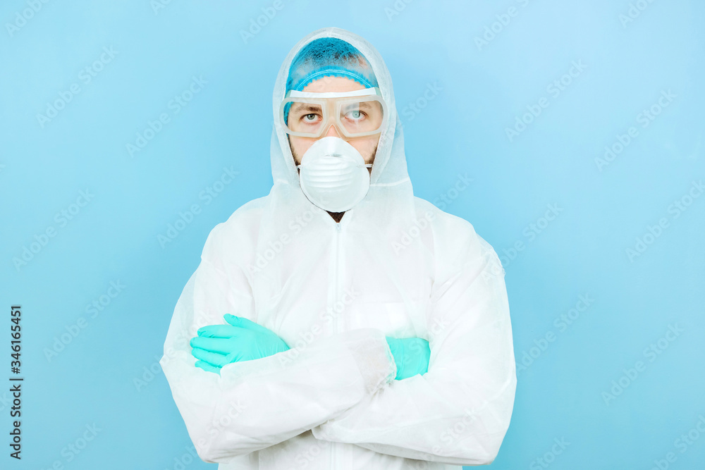 portrait of tired doctor after shift in the hospital. The doctor in protective clothing - glasses, mask, gloves on blue background. The doctor treating patients with coronavirus. Covid-2019 portrait of tired doctor after shift in the hospital. The doctor in protective clothing - glasses, mask, gloves on blue background. The doctor treating patients with coronavirus. Covid-2019