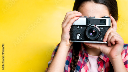 Young girl taking a picture with a retro camera. Home leisure lifestyle.