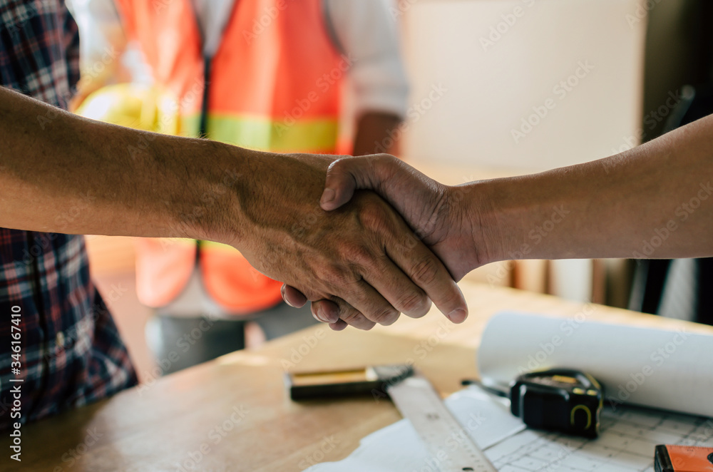 engineer, interior designer and architect hands shaking greeting start up plan new project contract with blueprint on desk in meeting room office at construction site, partnership, contractor concept engineer, interior designer and architect hands shaking greeting start up plan new project contract with blueprint on desk in meeting room office at construction site, partnership, contractor concept