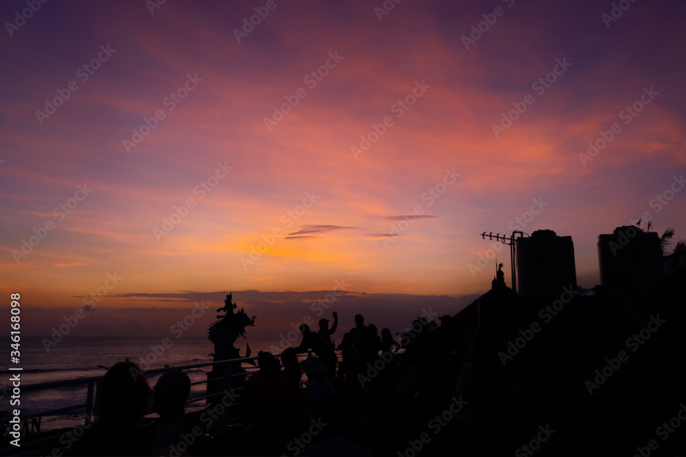 an observation deck overlooking the Indian ocean at sunset, with blurred silhouettes of people having fun on a summer evening and enjoying the sunset