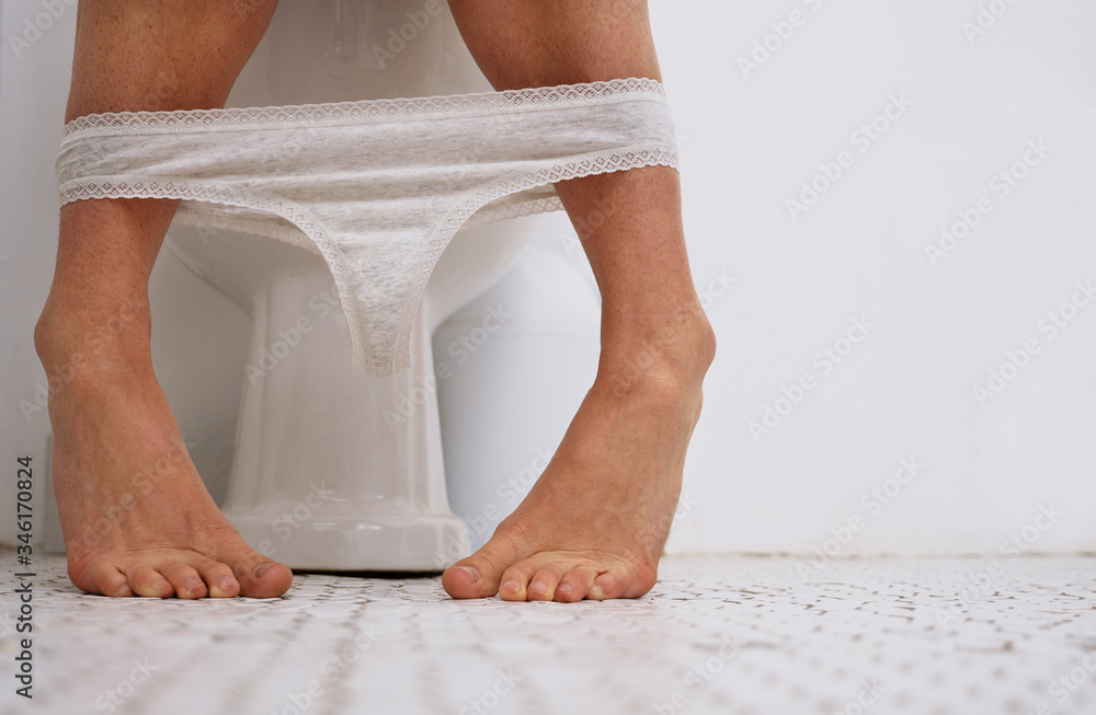 Woman sitting on the toilet with her panties down Stock Photo
