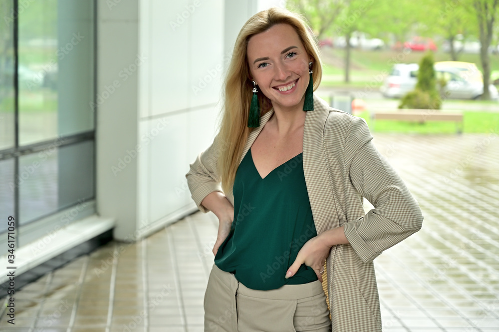 Portrait of a young business woman blonde smiling on a background of a city outdoors. Model posing in a business suit. Portrait of a young business woman blonde smiling on a background of a city outdoors. Model posing in a business suit.