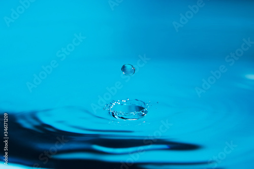 Beautiful splash of water drop on water surface in blue, macro
