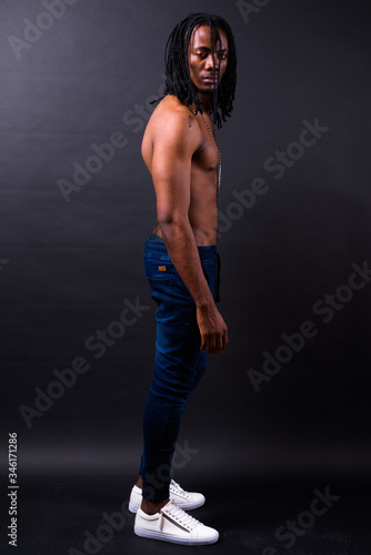 Full body shot of young handsome muscular African man with dreadlocks shirtless