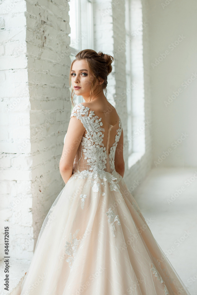 bride in white wedding dress. happy beautiful young woman in white traditional wedding dress on white background. big windows and white walls. bride in white wedding dress. happy beautiful young woman in white traditional wedding dress on white background. big windows and white walls.