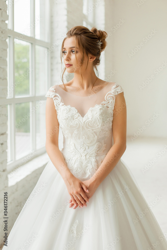 bride in white wedding dress. happy beautiful young woman in white traditional wedding dress on white background. big windows and white walls. bride in white wedding dress. happy beautiful young woman in white traditional wedding dress on white background. big windows and white walls.