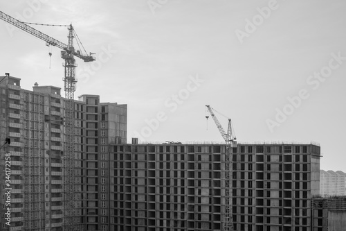 Construction of a large high-rise building with cranes with the grey sky background. Black and White.