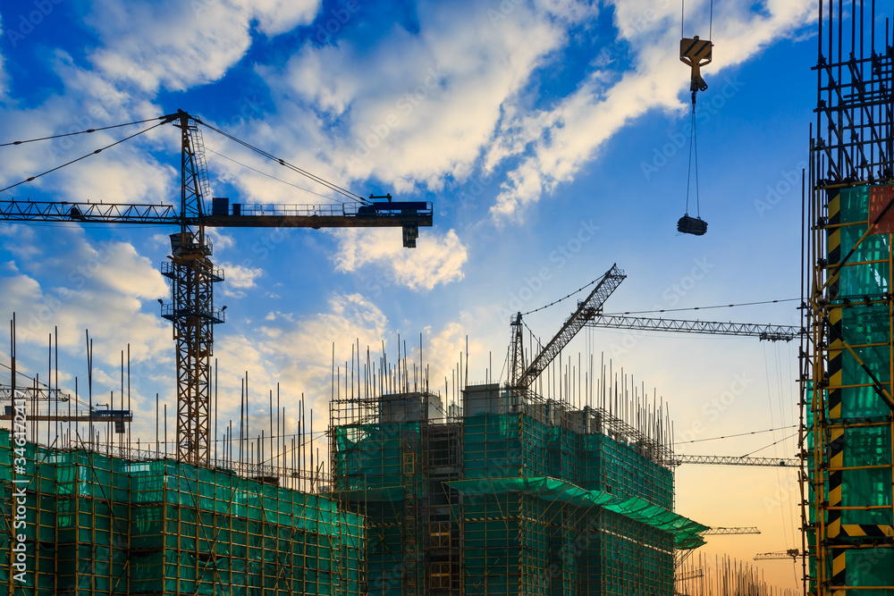 Tower crane and building construction site silhouette at sunrise. Tower crane and building construction site silhouette at sunrise.