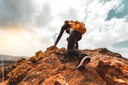 Success woman hiker hiking on sunrise mountain peak - Young woman with backpack rise to the mountain top. Discovery Travel Destination Concept photo