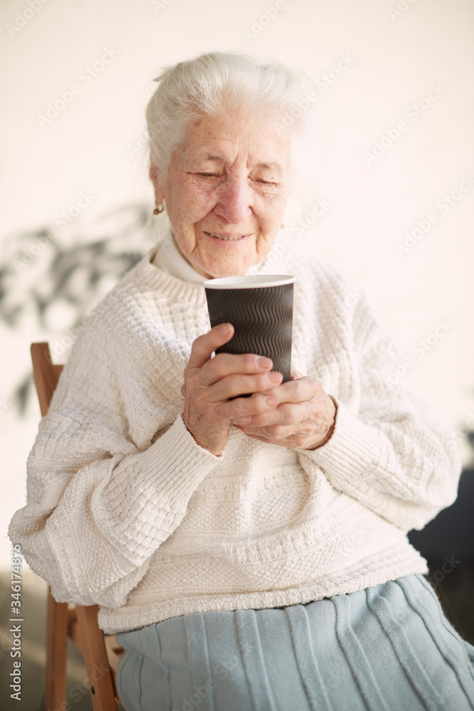 Grandmother is sitting in the chair and drinking tea. Granny at home. Beautiful old woman portrait. Grandmother is sitting in the chair and drinking tea. Granny at home. Beautiful old woman portrait.