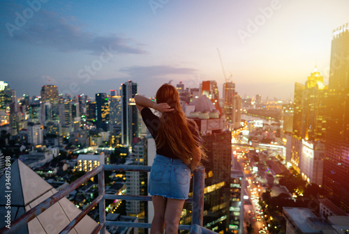 Photography Young asian woman looking on rooftop during sunset with skylines Bangkok, Thailand