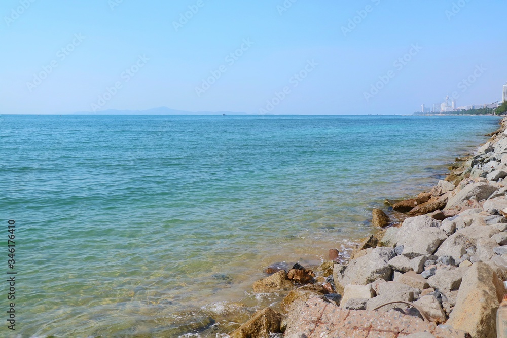 Beautiful view of  rocky shore with waves crashing and clear blue sky in summer time. Nature and outdoor concept.