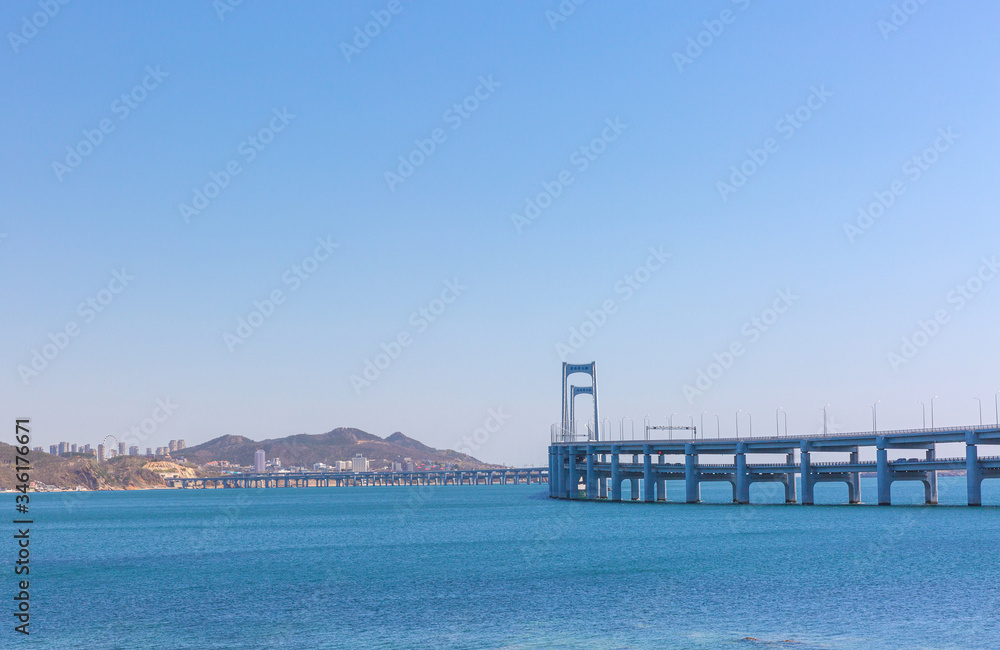 Obraz premium Black stone and city cross-sea bridge in the sea in Dalian, Liaoning, China in the morning
