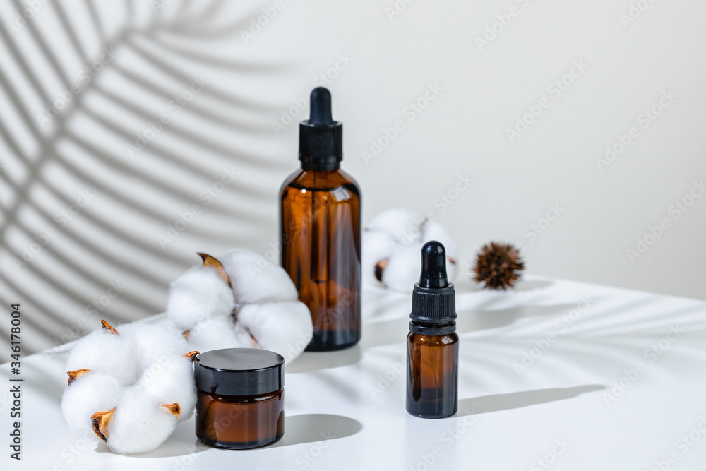 Creative photo of cosmetic bottle with pipette on a white background with shadow of tropical flower. Advertising Creative photo of cosmetic bottle with pipette on a white background with shadow of tropical flower. Advertising