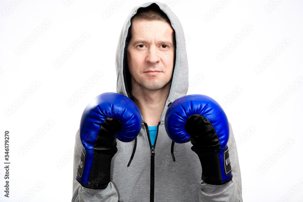 A confident calm athlete holds his hands in boxing gloves in front of him. Dressed in a sports jacket, looking at the camera. Close-up, isolated A confident calm athlete holds his hands in boxing gloves in front of him. Dressed in a sports jacket, looking at the camera. Close-up, isolated