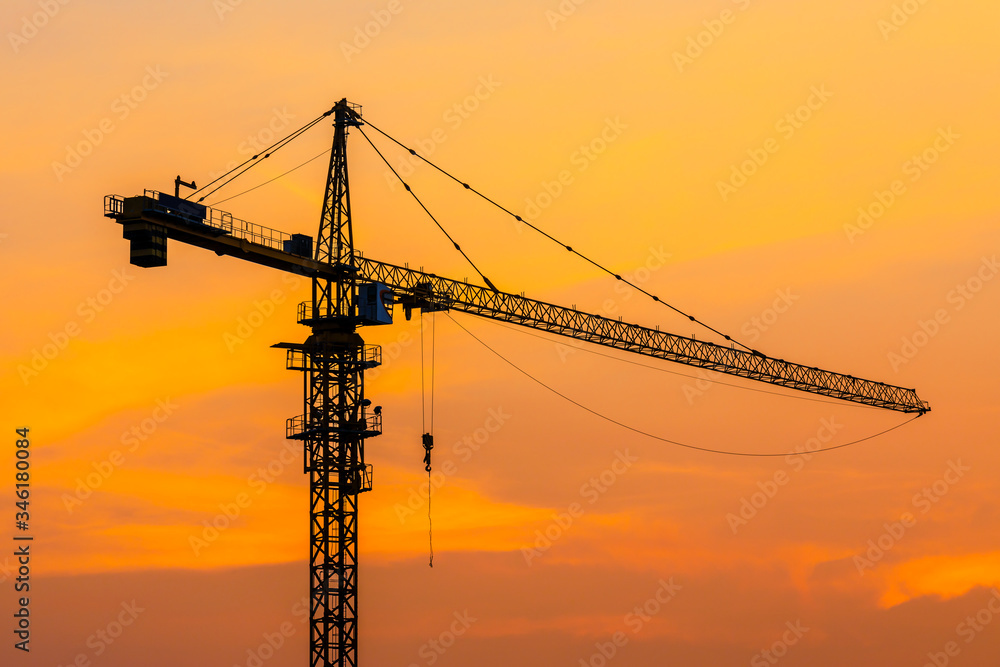 Tower crane and building construction site silhouette at sunrise. Tower crane and building construction site silhouette at sunrise.