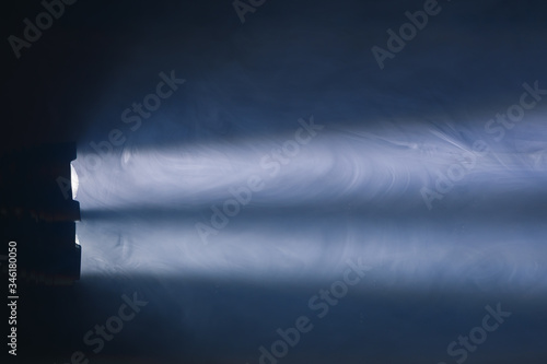 ray of pocket flashlight in smoke, copy-space background © nikkytok