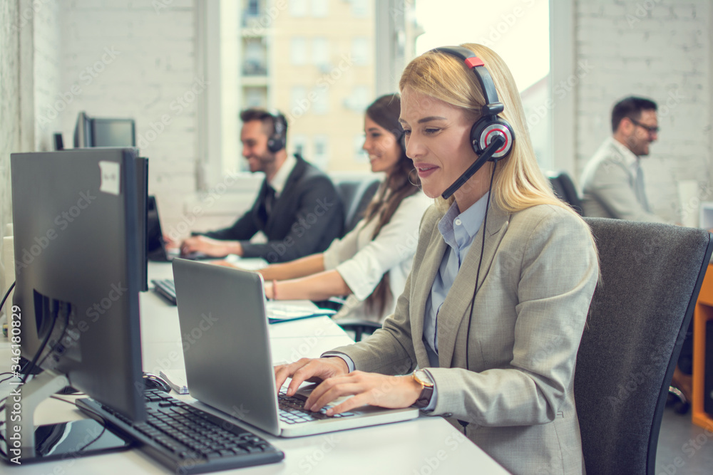 Beautiful young woman with headset using laptop while talking with a client. Online customer care support service. Beautiful young woman with headset using laptop while talking with a client. Online customer care support service.