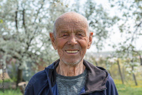 Close up portrait of a happy old man pensioner in sportswear who smiling and looking at the camera