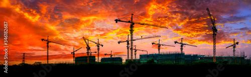 Tower crane and building construction site silhouette at sunrise.panoramic view.