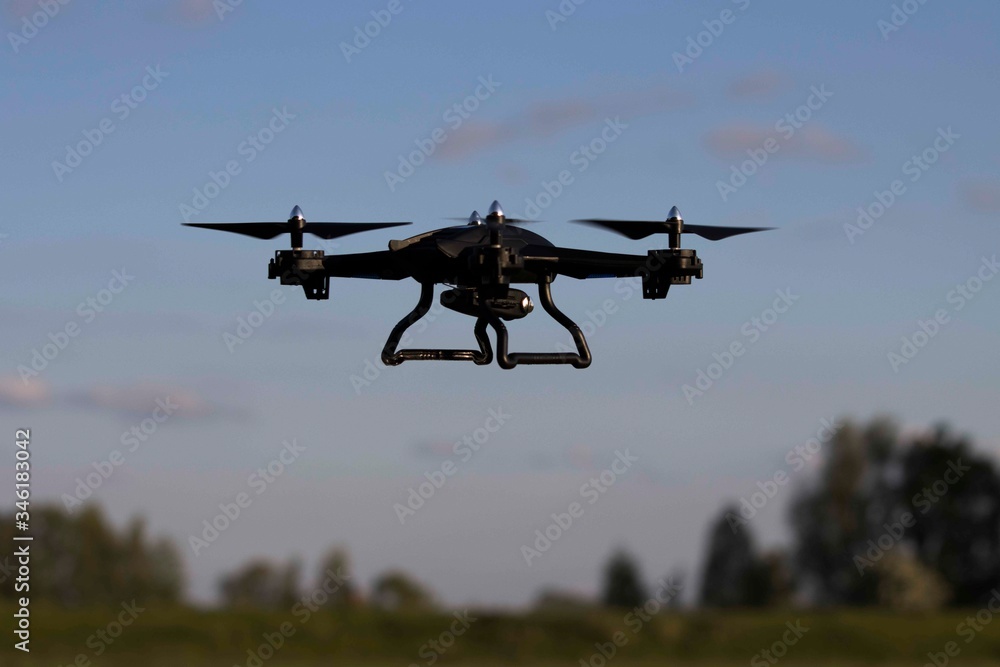 Drone flying in blue cloudy sky close up, quadcopter helicopter Drone flying in blue cloudy sky close up, quadcopter helicopter