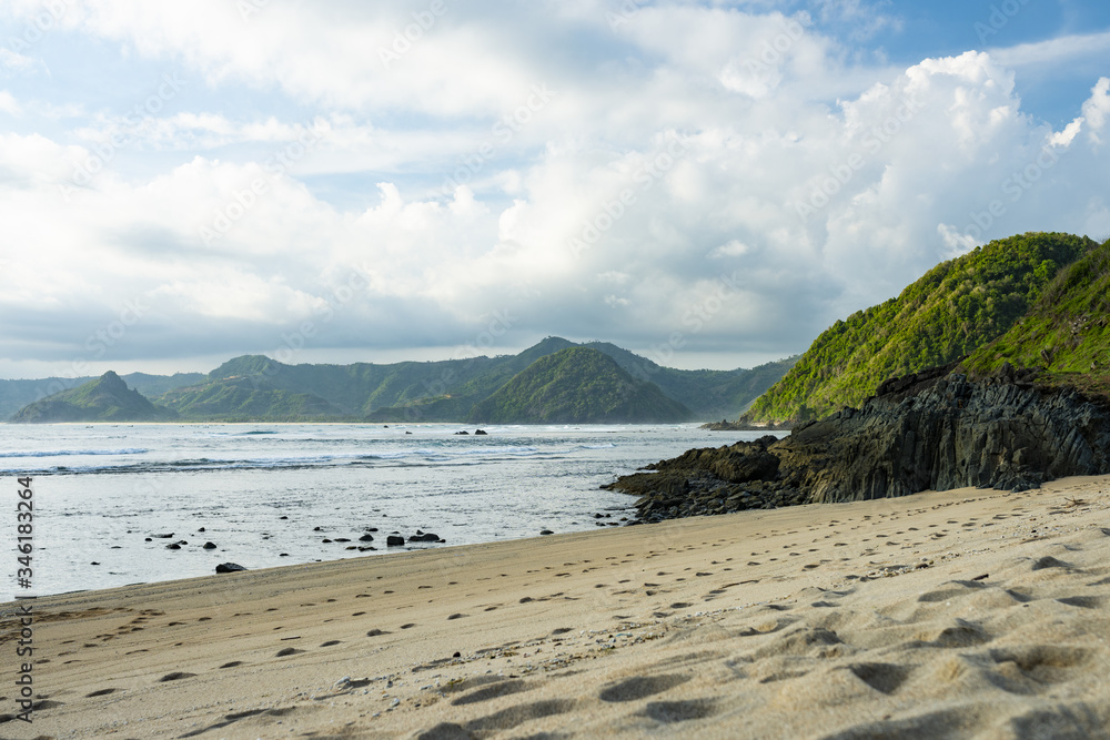 Stunning view of the Selong Belanak beach flanked by a green mountainous coast. Selong Belanak Beach is a beautiful white sand beach located in Lombok, West Nusa Tenggara, Indonesia