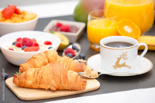 Breakfast Served in the morning with Butter croissant and corn flakes Whole grains and raisins with milk in cups and Strawberry  Blueberry  Raspberry  Kiwi  Fresh Orange Juice on the breakfast table.