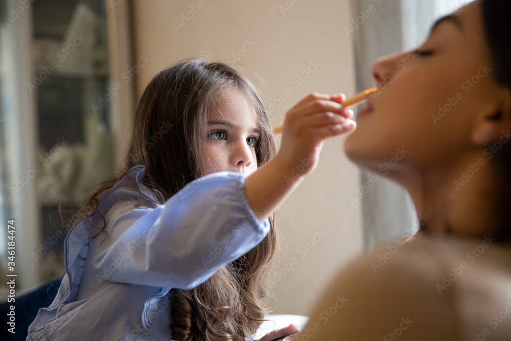 Happy loving family. Mother and daughter are doing make up and having fun at home. Close up portrait of daughter making up on her mom's face. Happy loving family. Mother and daughter are doing make up and having fun at home. Close up portrait of daughter making up on her mom's face.