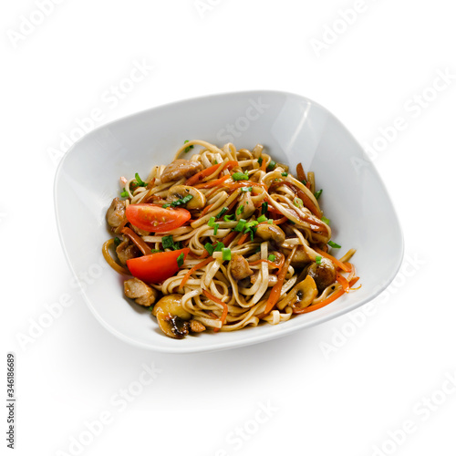 Fried udon noodles in a wok with slices of pork, carrots and mushrooms. Traditional asian food. Isolated on a white background.