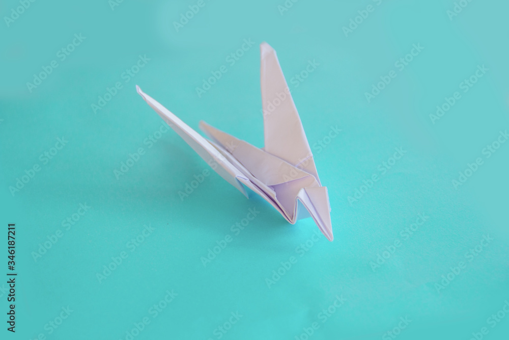 Origami white swallow on a blue isolated background. board, World Peace Day concept. Close up studio photo. child made bird, craft, hobby and creativity concept Origami white swallow on a blue isolated background. board, World Peace Day concept. Close up studio photo. child made bird, craft, hobby and creativity concept