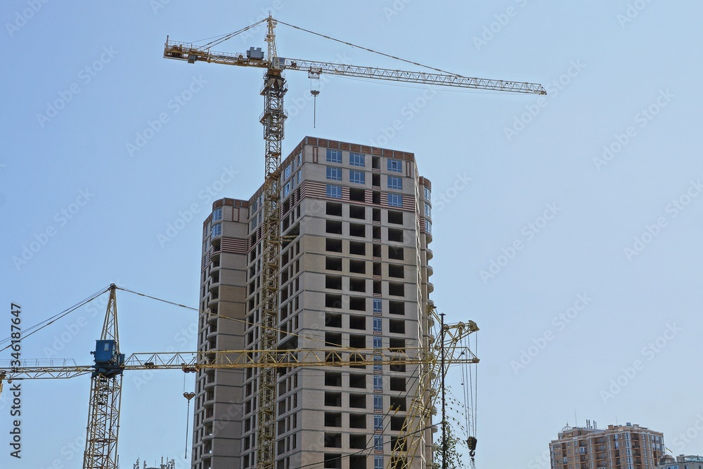 two an iron tower crane and a large unfinished brown house against the sky two an iron tower crane and a large unfinished brown house against the sky