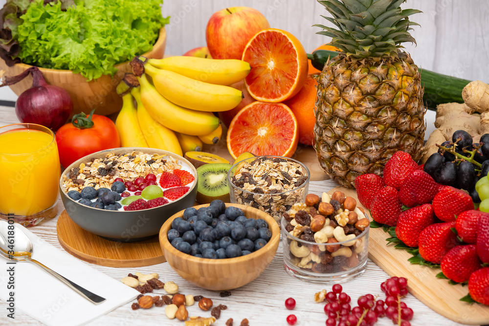 Group Fruits Breakfast mixed vegetables with salad bowl, nuts bowl, strawberry, banana, and pineapple, orange juice, vitamin c in food nature for health and diet in the top view on the wood table. Group Fruits Breakfast mixed vegetables with salad bowl, nuts bowl, strawberry, banana, and pineapple, orange juice, vitamin c in food nature for health and diet in the top view on the wood table.
