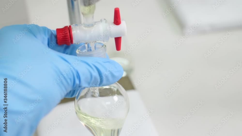 Scientists wear blue gloves and collect a sample from the glass column into a glass bottle in the laboratory. Shake glass bottle to mix samples together. Industrial and education concept. Scientists wear blue gloves and collect a sample from the glass column into a glass bottle in the laboratory. Shake glass bottle to mix samples together. Industrial and education concept.
