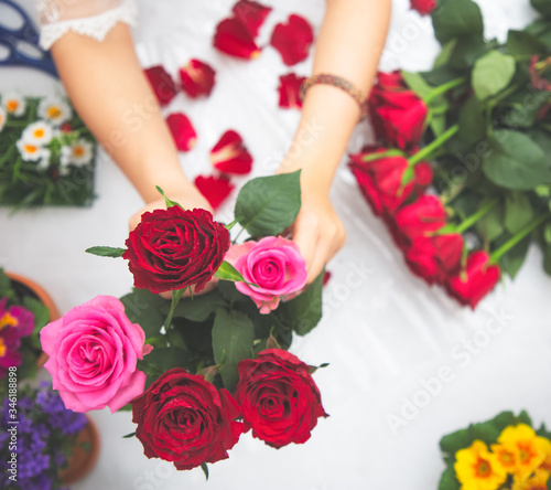 Woman Preparing to trim red and pink roses and beautiful flower arrangements in the home, flower arrangements with vase for gift-giving for Valentine's Day and Business in the family on the on table
