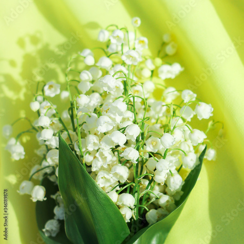 Beautiful bouquet of lilies of the valley on a yellow background, top view