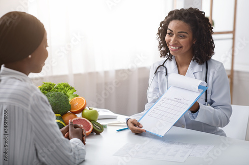 Woman dietician showing female patient medical chart