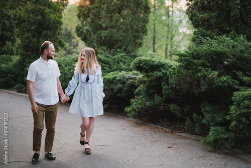 Romantic and happy caucasian couple in casual clothes hugging on the background of beautiful nature. Love, relationships, romance, happiness concept. Man and woman walking outdoors together.