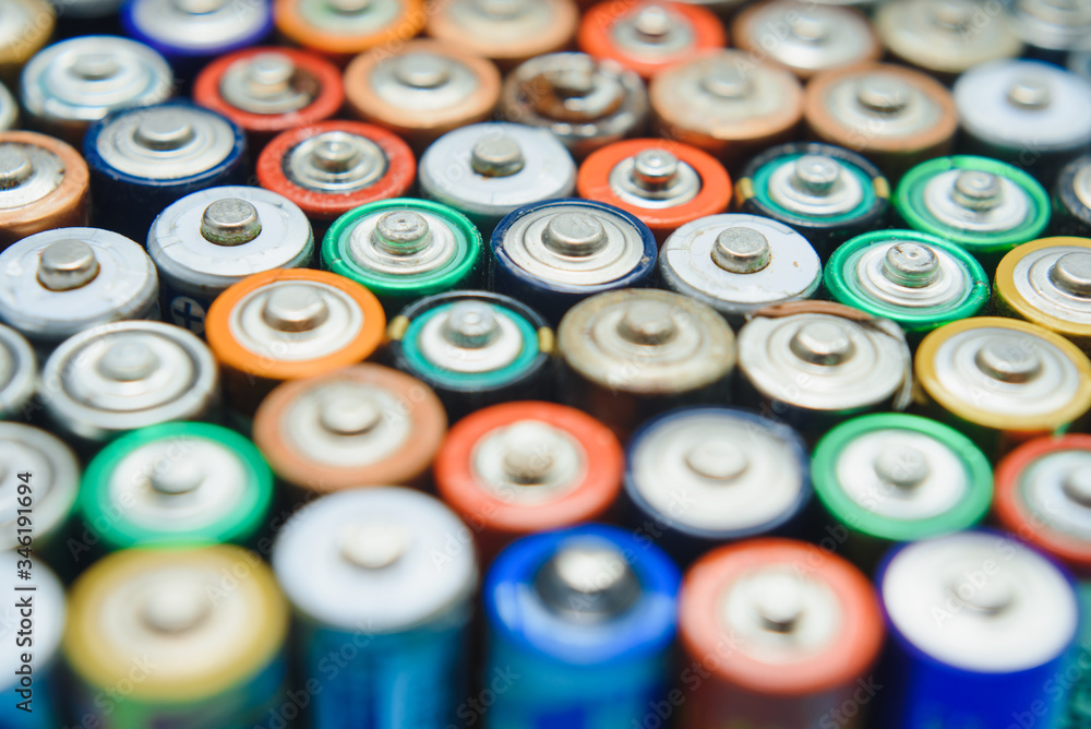 Close up of positive ends of colorful discharged batteries of different sizes and formats, top view, copy space. Used alkaline battery on concrete background. Hazardous garbage concept. Close up of positive ends of colorful discharged batteries of different sizes and formats, top view, copy space. Used alkaline battery on concrete background. Hazardous garbage concept.