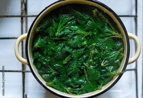 Young nettle leaves cooking in saucepan on top of a stove