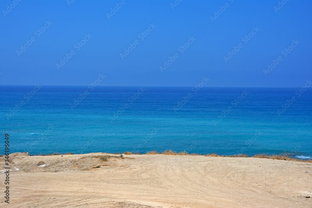 A strip of sandy beach and a sea horizon with a clear cloudless sky