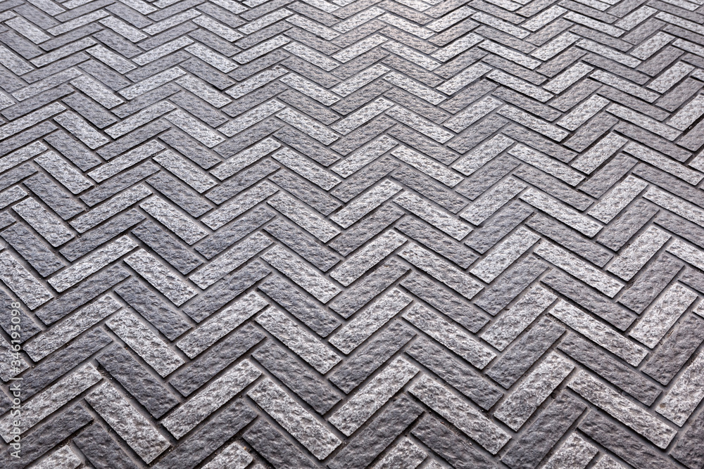Grey paving slabs made of natural stone laid with a herringbone pattern Grey paving slabs made of natural stone laid with a herringbone pattern