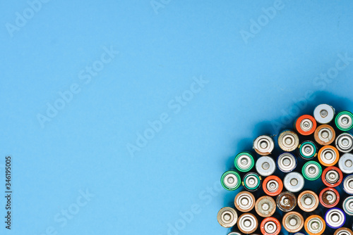 Close up of positive ends of colorful discharged batteries of different sizes and formats, top view, copy space. Used alkaline battery on concrete background. Hazardous garbage concept.