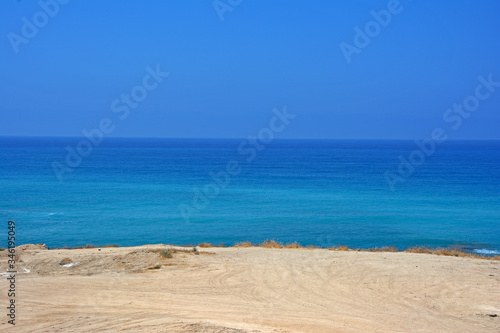 A strip of sandy beach and a sea horizon with a clear cloudless sky
