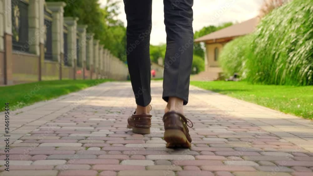 The legs of a man in shoes and trousers are walking in the park along the stone sidewalk. 4K footage The legs of a man in shoes and trousers are walking in the park along the stone sidewalk. 4K footage