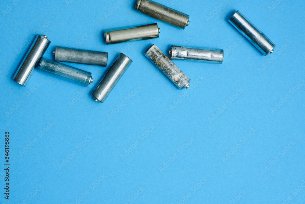 Scattered old dirty batteries aa or aaa size on blue background. Recycling concept. Save environment. Alternative energy Scattered old dirty batteries aa or aaa size on blue background. Recycling concept. Save environment. Alternative energy