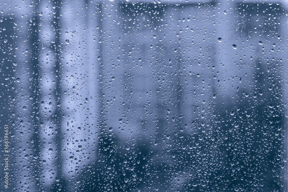 rainy droplets on a blue window glass transparent surface. drops on window shield in a rainy days  in night city. stormy weather. isolation sad depression concept.  rainy season.