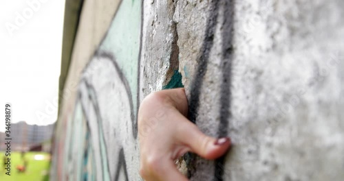 Woman hand reaches through hold in Berlin Wall