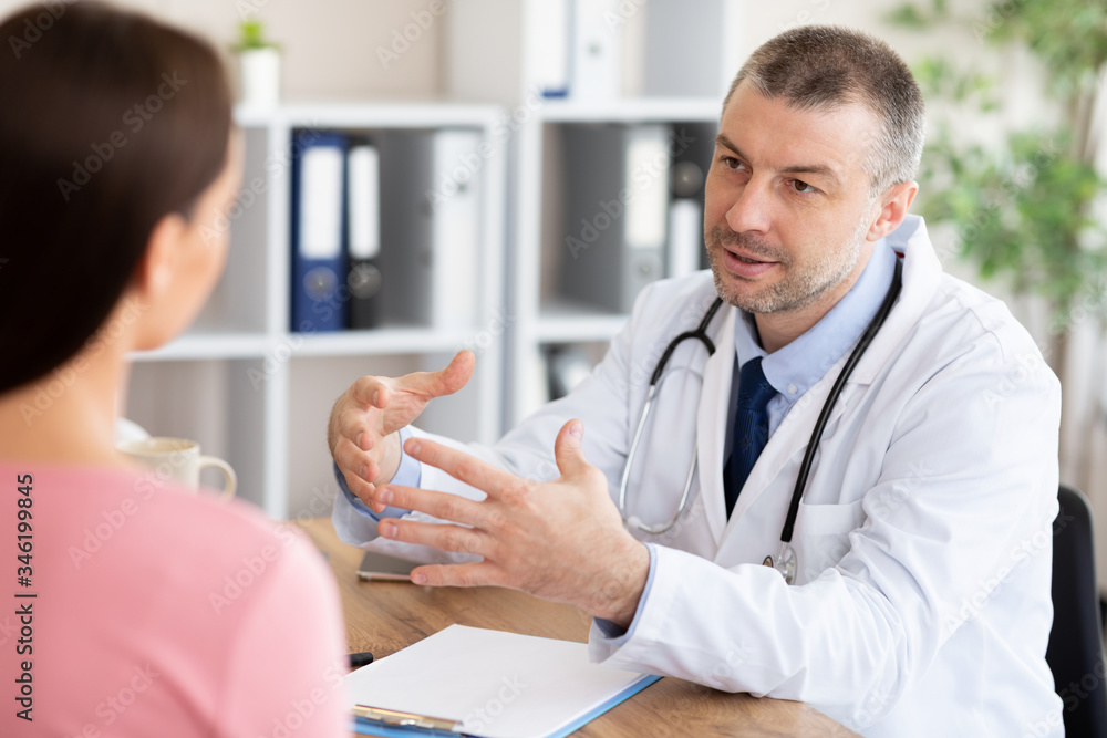 Obraz premium Male experienced doctor talking with his female patient
