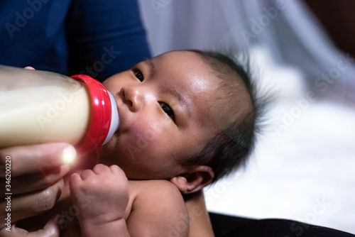 Newborn baby sucking milk from a bottle,Pure clear eyes,blurry light around,Lens flare effect