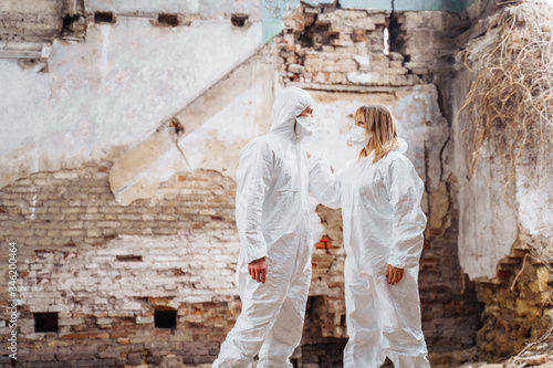 Fototapeta Naklejka Na Ścianę i Meble -  Doctors saving lives in an abandoned building. War in the city, emergency, cataclysm. Doctors are glad they saved people, hugging. People in protective clothing are standing on the ruins of a house.